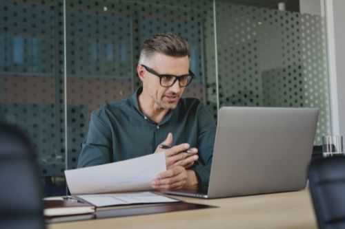 man with glasses on video call via laptop