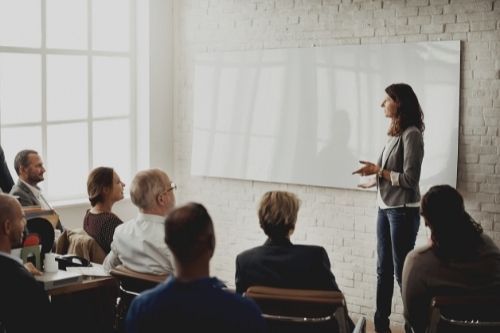 woman teaching group of people with white board