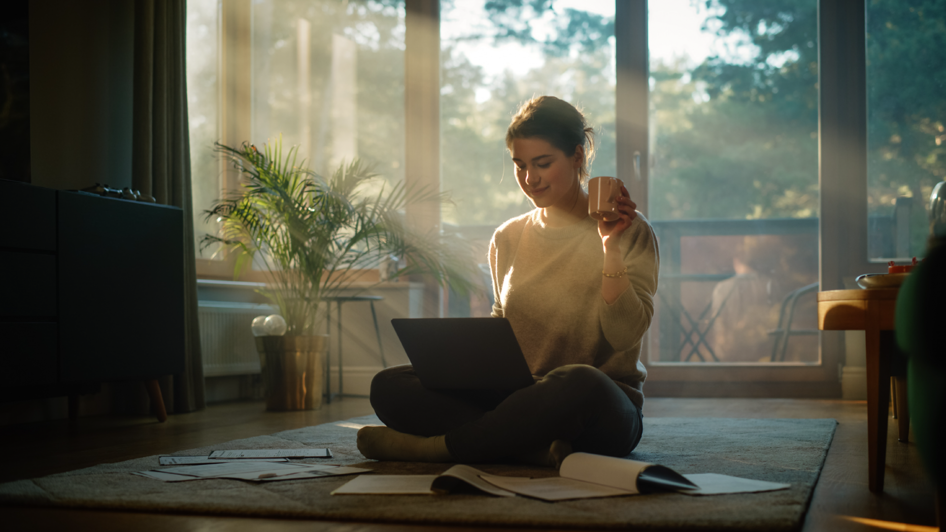 relaxed woman in front of laptop with cup in hand